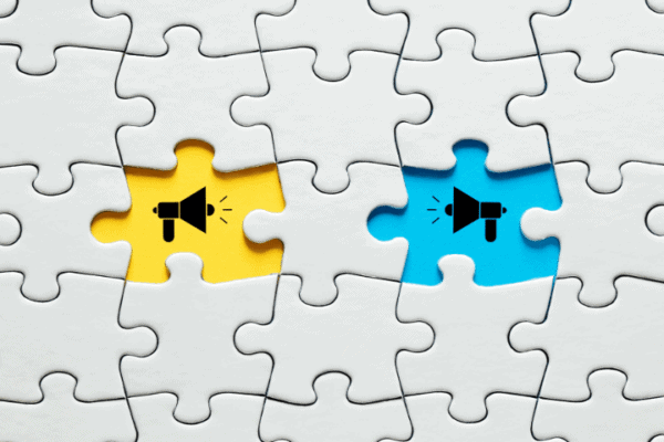 jigsaw puzzle with two missing pieces and the background is blue and yellow with megaphones
