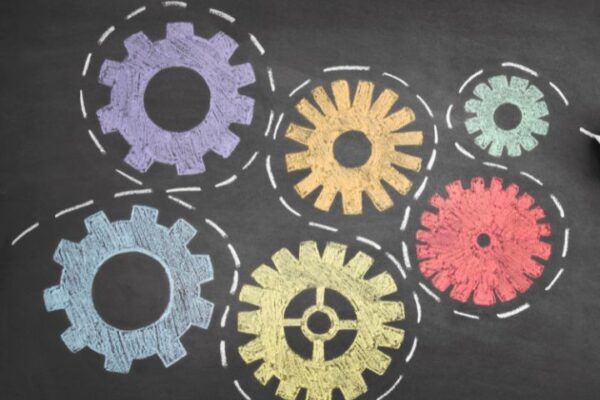 A person drawing gears on a blackboard.